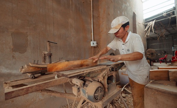 Artisan menuisier découpant une pièce de bois dans son atelier